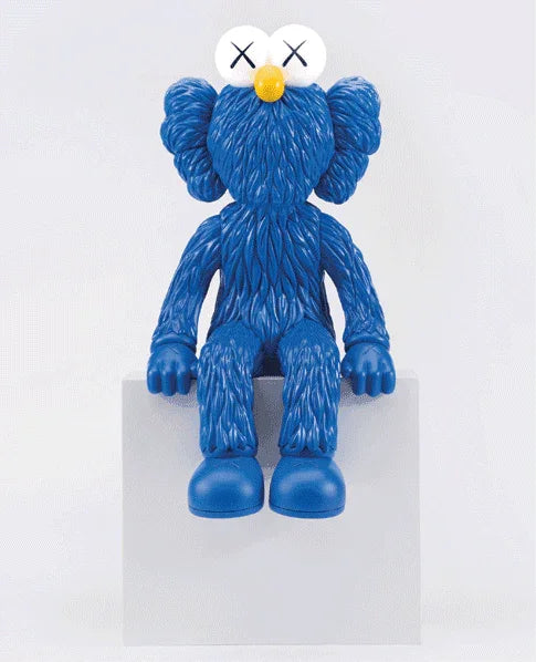 Blue textured KAWS collectible figurine with crossed-out eyes sitting on white pedestal